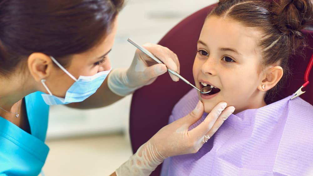 a dentist checks a girl's teeth